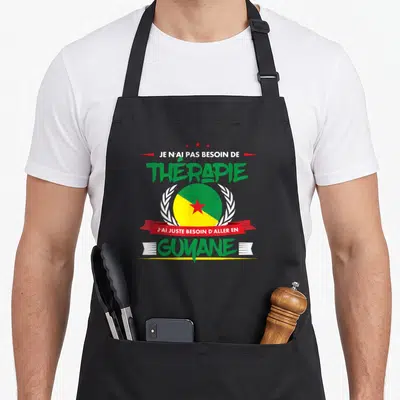 Tablier de cuisine noir avec le texte Je n'ai pas besoin de thérapie J'ai juste besoin d'aller en Guyane et un drapeau circulaire.