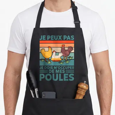 Tablier de cuisine noir avec trois poules colorées et le texte Je peux pas je dois m'occuper de mes poules en bleu turquoise.