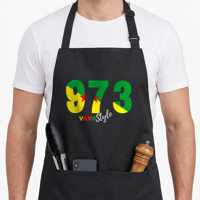 Tablier de cuisine noir avec l'inscription 973 aux couleurs vert jaune et rouge et le texte Yana Style en dessous.