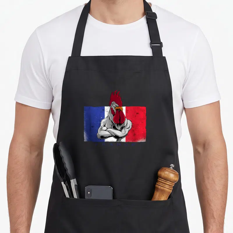 Tablier de cuisine noir avec illustration d'un coq aux bras croisés devant le drapeau français et le mot FRANCE en bas.