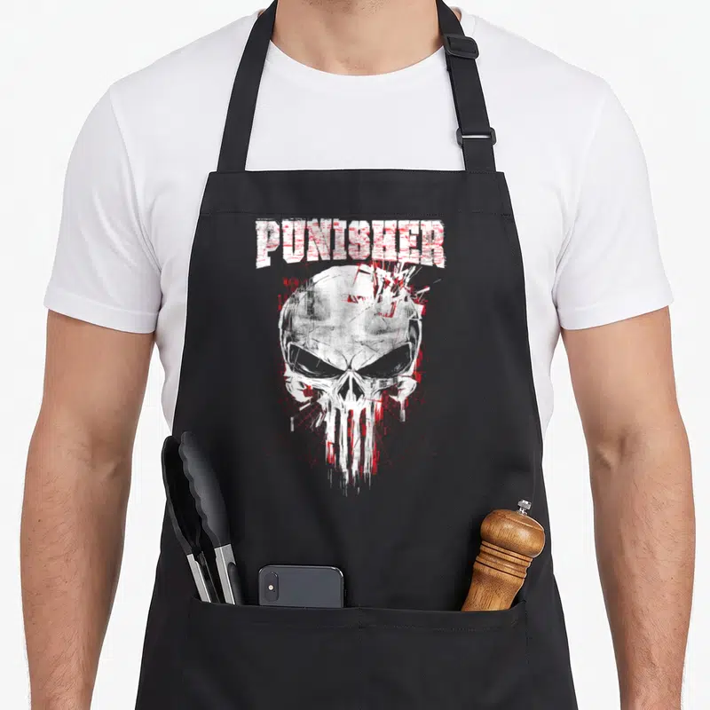 Tablier de cuisine noir avec illustration d'un crâne blanc et rouge et le texte PUNISHER en haut.