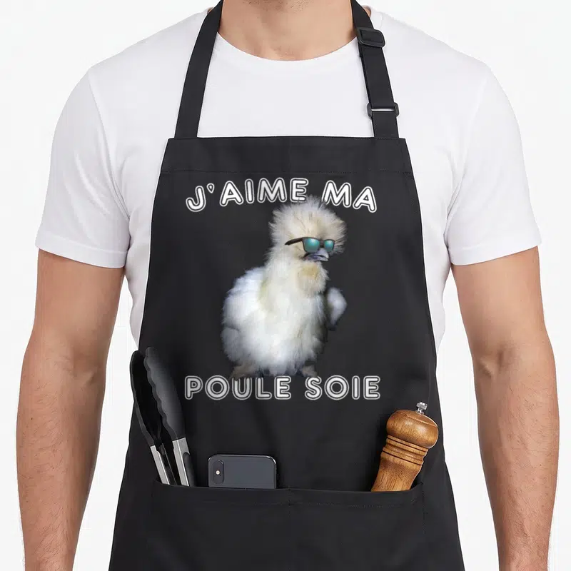 Tablier de cuisine noir avec une illustration d'une poule soie portant des lunettes de soleil et du texte en blanc.