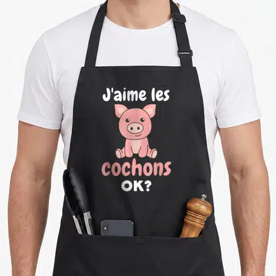 Tablier de cuisine noir avec un cochon rose assis et l'inscription J'aime les cochons OK ?, design mignon et drôle.