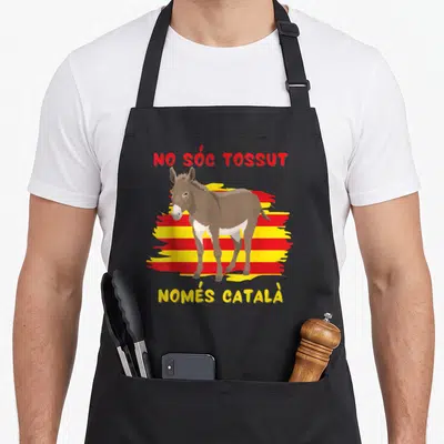 Tablier de cuisine noir avec illustration d'un âne devant un drapeau catalan aux rayures rouges et jaunes.