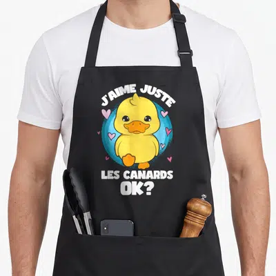 Tablier de cuisine noir avec illustration d'un canard jaune et texte J'aime juste les canards OK surrounded by pink hearts.