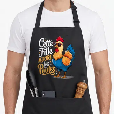 Tablier de cuisine noir avec un coq stylisé aux verres fumés et l'inscription Cette Fille Adore les Poules en typographie colorée.
