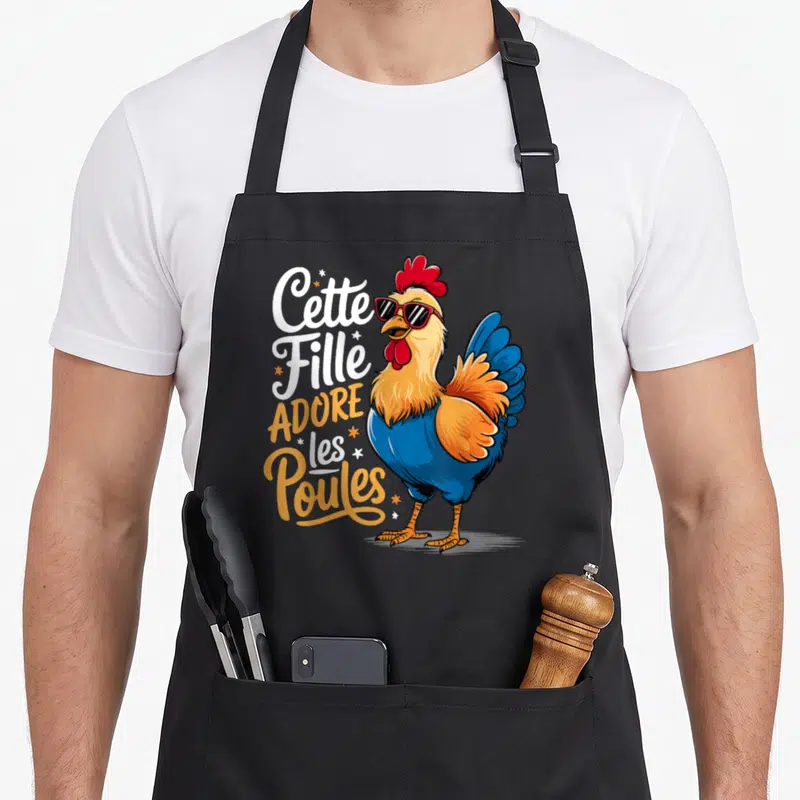 Tablier de cuisine noir avec un coq stylisé aux verres fumés et l'inscription Cette Fille Adore les Poules en typographie colorée.