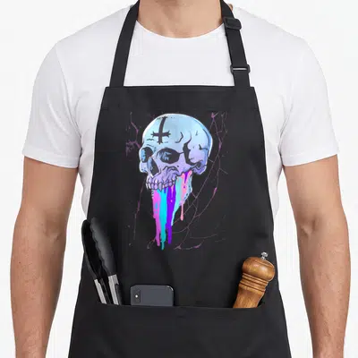 Tablier de cuisine noir avec illustration d'un crâne goth pastel aux couleurs vives et croix sur le front.