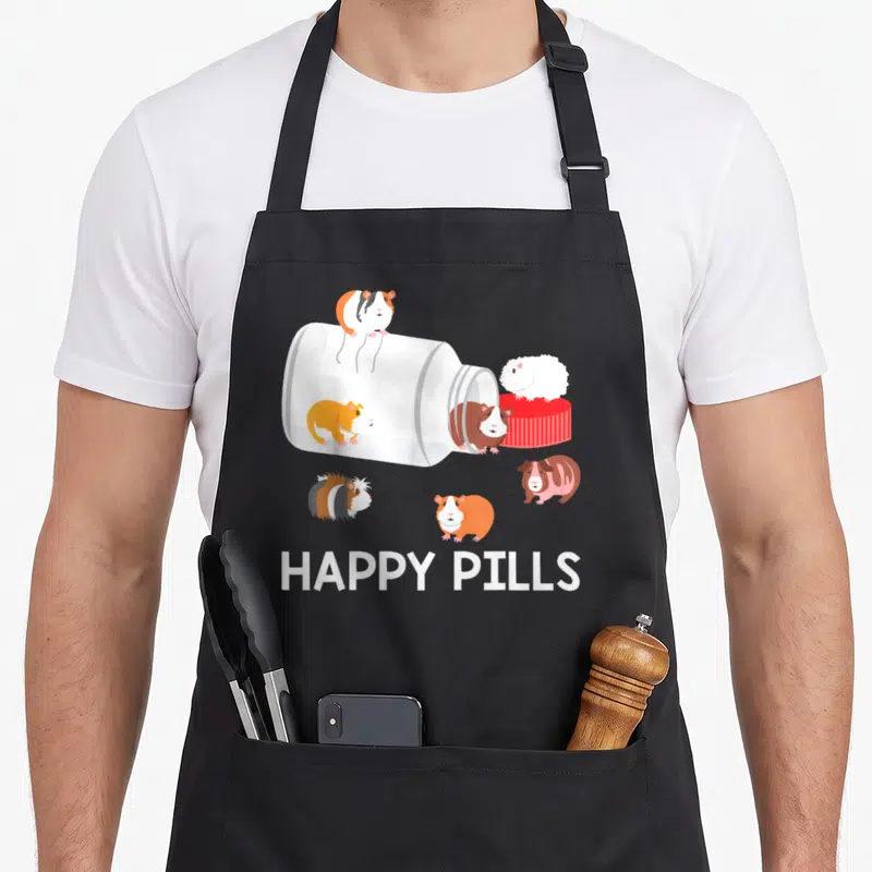 Tablier de cuisine noir avec illustration de flacon renversé contenant divers cochons d'Inde colorés et l'inscription Happy Pills en bas.