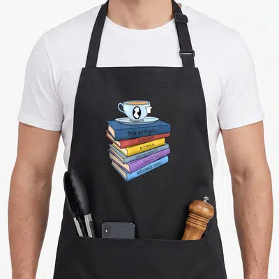 Tablier de cuisine noir avec une illustration d'une pile de livres de Jane Austen surmontée d'une tasse de thé bleue.