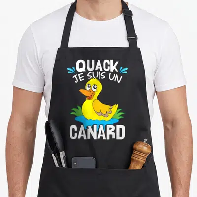 Tablier de cuisine noir avec illustration colorée d'un canard jaune et du texte Quack je suis un canard imprimé en blanc.