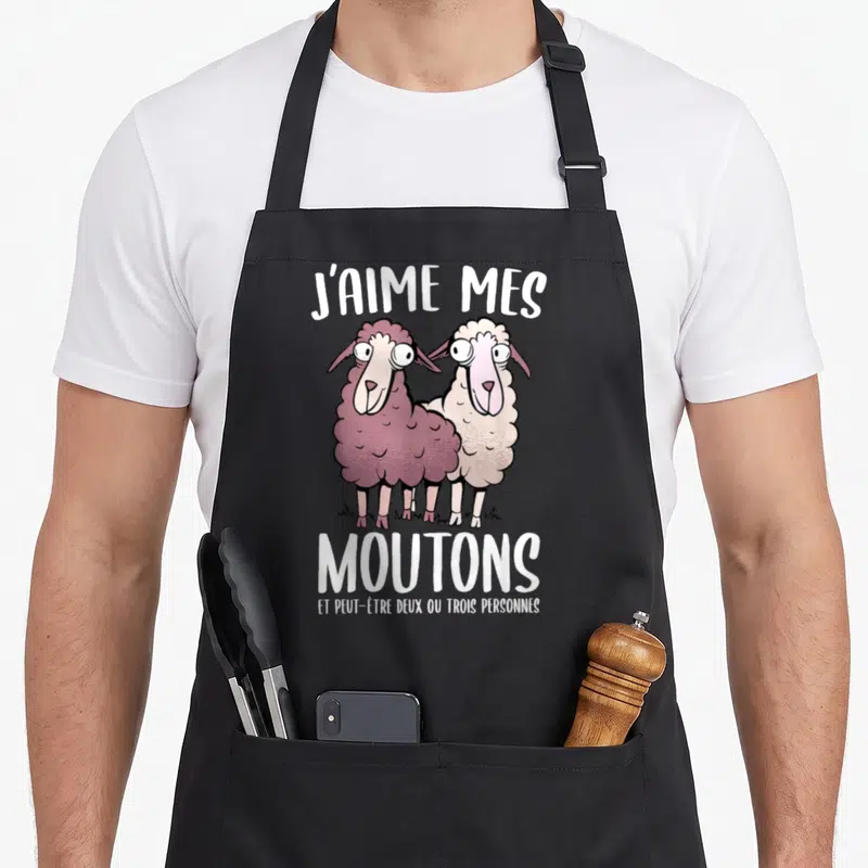 Tablier de cuisine noir avec l'illustration de deux moutons colorés et un texte humoristique en blanc.