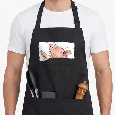 Tablier de cuisine noir avec illustration d'un cochon rose dormant sur un oreiller blanc et le texte Chemise de nuit préférée.
