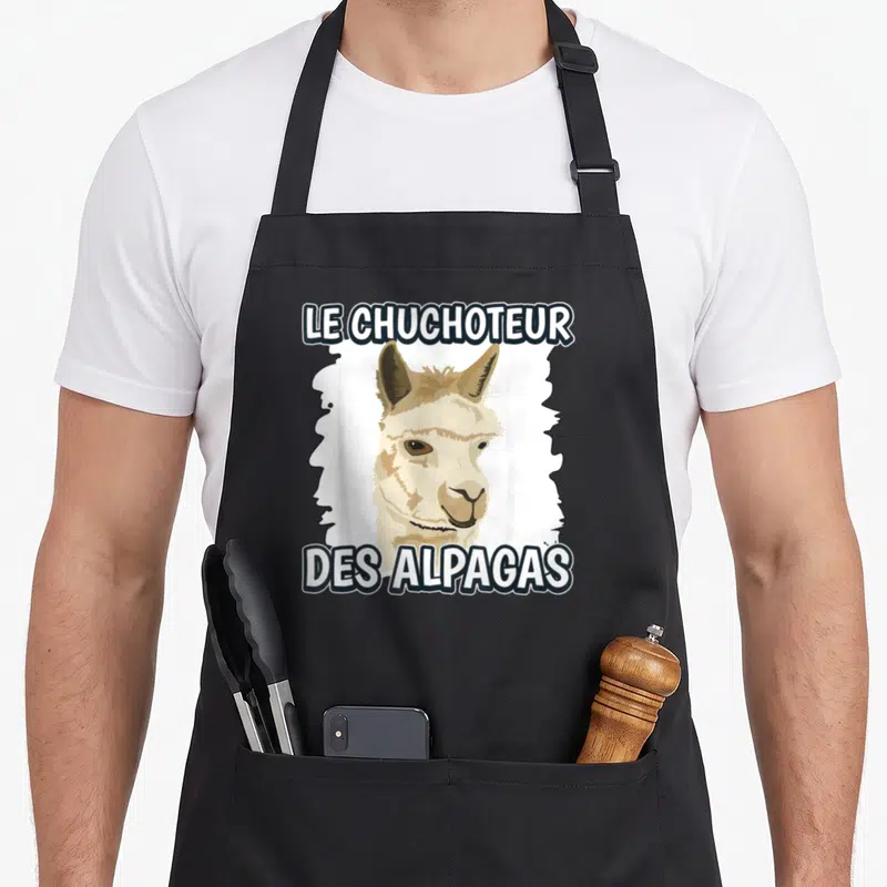 Tablier de cuisine noir avec illustration d'alpaga beige et texte blanc Le Chuchoteur des Alpagas.