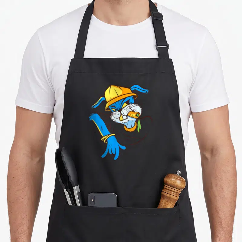 Tablier de cuisine noir avec illustration d'un lapin rappeur bleu portant une casquette jaune et tenant une carotte orange dans sa bouche.