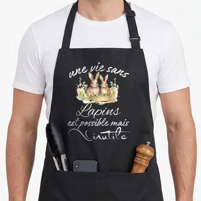 Tablier de cuisine noir avec deux lapins en aquarelle entourés de fleurs et le texte une vie sans lapins est possible mais inutile.