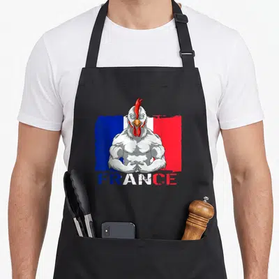 Tablier de cuisine noir avec illustration d'un coq musclé sur fond de drapeau français et texte FRANCE en bas.