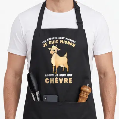 Tablier de cuisine noir avec illustration d'une chèvre beige et le texte Les chèvres sont mignons je suis mignon alors je suis une chèvre
