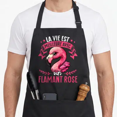 Tablier de cuisine noir avec illustration colorée d'un flamant rose et texte blanc sur banderole rose.