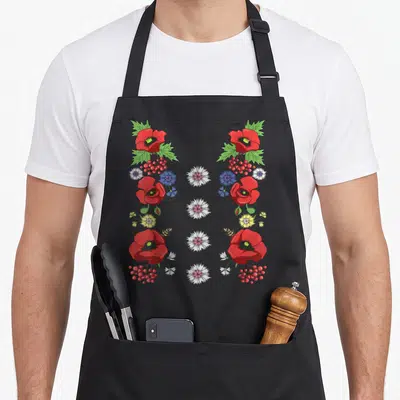 Tablier de cuisine noir avec des coquelicots rouges, des baies, du bleuet et des fleurs blanches disposés en colonnes verticales.