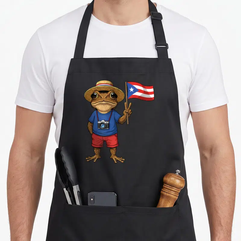 Tablier de cuisine noir avec une grenouille Coqui portant un chapeau et tenant le drapeau de Porto Rico.
