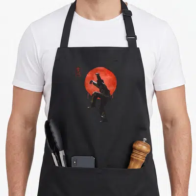 Tablier de cuisine noir avec illustration d'un karatéka effectuant un saut de l'hirondelle devant un cercle rouge style encre sumi.