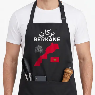 Tablier de cuisine noir avec carte rouge du Maroc, drapeau vert et texte blanc BERKANE en arabe et latin.