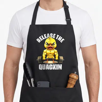 Tablier de cuisine noir avec un canard jaune musclé soulevant une barre et le texte Release The Quackin imprimé en blanc.