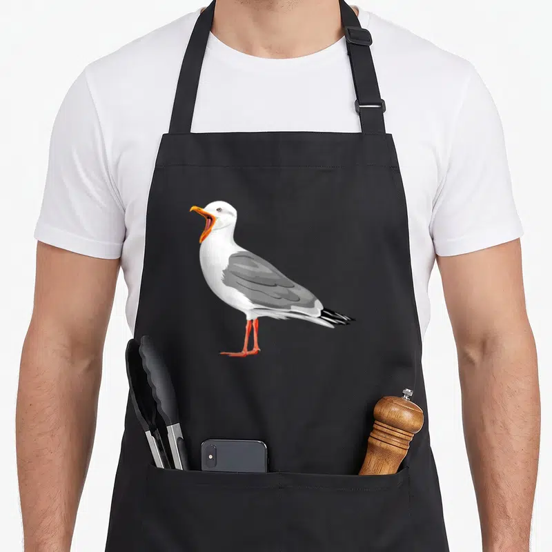 Tablier de cuisine noir avec une illustration de mouette blanche et grise au bec orange ouvert.