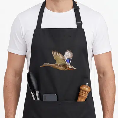 Tablier de cuisine noir avec illustration réaliste d'un canard colvert en plein vol aux ailes déployées.