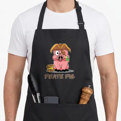 Tablier de cuisine noir avec illustration d'un cochon pirate rose portant un chapeau et tenant un perroquet près d'un coffre.