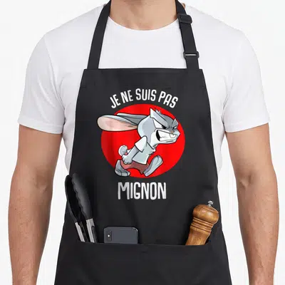 Tablier de cuisine noir avec illustration d'un lapin gris grincheux et du texte Je ne suis pas mignon en blanc.