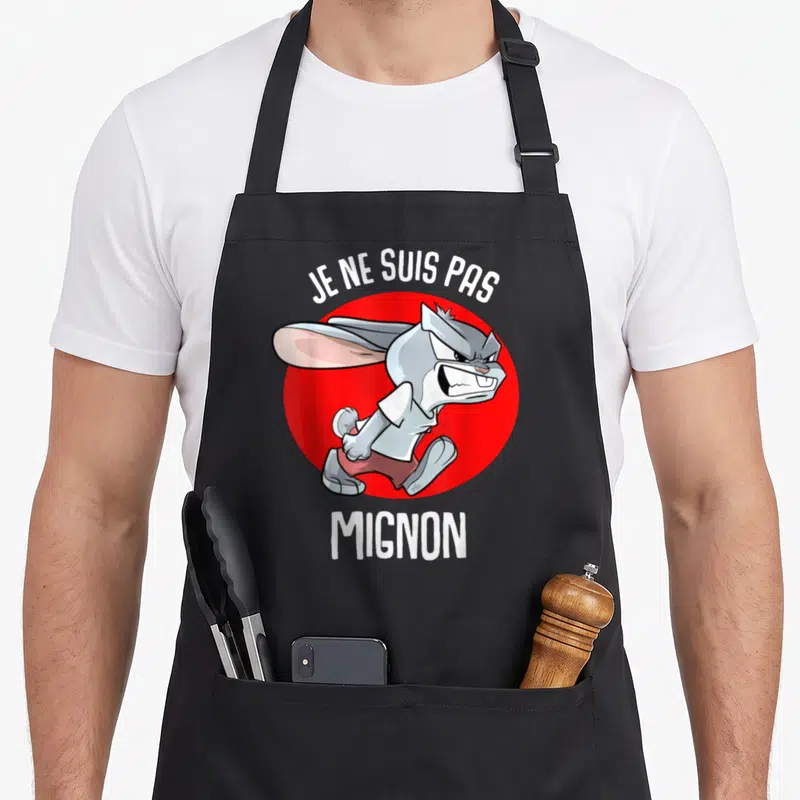 Tablier de cuisine noir avec illustration d'un lapin gris grincheux et du texte Je ne suis pas mignon en blanc.