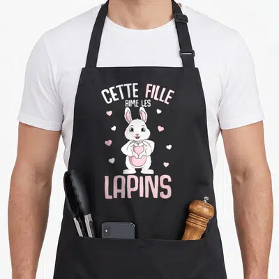 Tablier de cuisine noir avec illustration d'un lapin blanc tenant un cœur et le texte Cette Fille Aime Les Lapins.