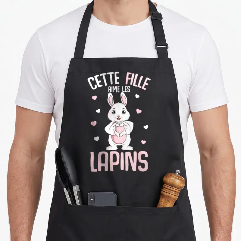 Tablier de cuisine noir avec illustration d'un lapin blanc tenant un cœur et le texte Cette Fille Aime Les Lapins.