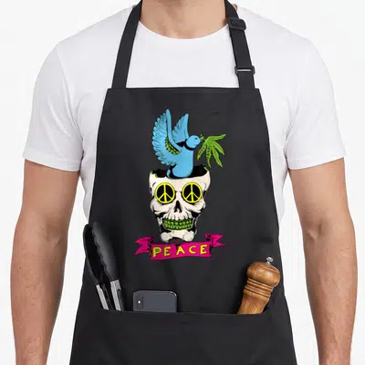 Tablier de cuisine noir avec un crâne portant des lunettes de paix, une colombe bleue et une banderole rosePEACE.