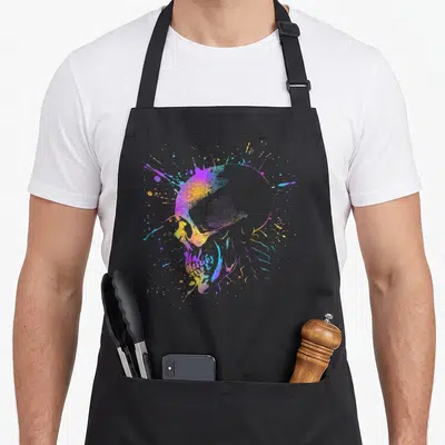 Tablier de cuisine noir avec illustration d'un crâne coloré artistique aux éclats de peinture multicolores.