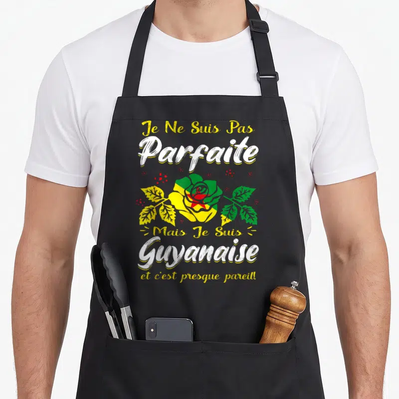 Tablier de cuisine noir avec une rose aux couleurs du drapeau de la Guyane et un texte humoristique en blanc et jaune.