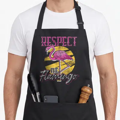 Tablier de cuisine noir avec illustration d'un flamant rose rose vif et texte Respectez Le Flamant Rose en style vintage.