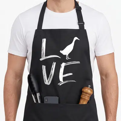 Tablier de cuisine noir avec le mot Love en lettres blanches et silhouette d'un canard coureur indien posé sur la lettre O.