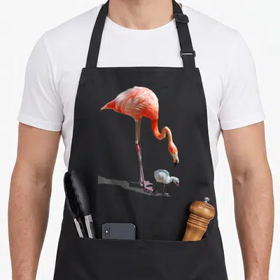Tablier de cuisine noir avec illustration d'un grand flamant rose orange et d'un petit cygne blanc en bas à droite.