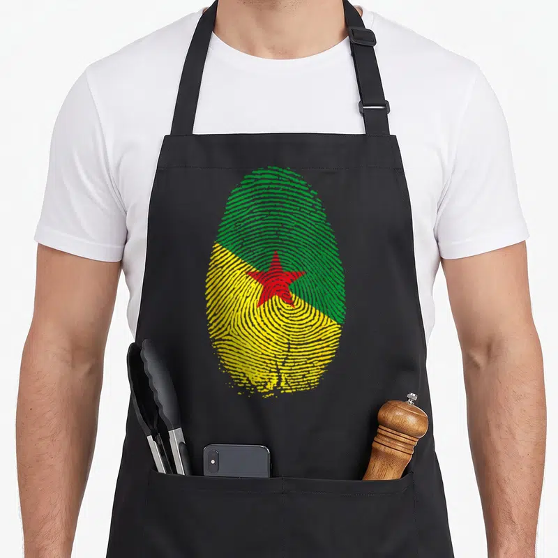 Tablier de cuisine noir avec une grande empreinte digitale aux couleurs du drapeau de la Guyane et une étoile rouge au centre.