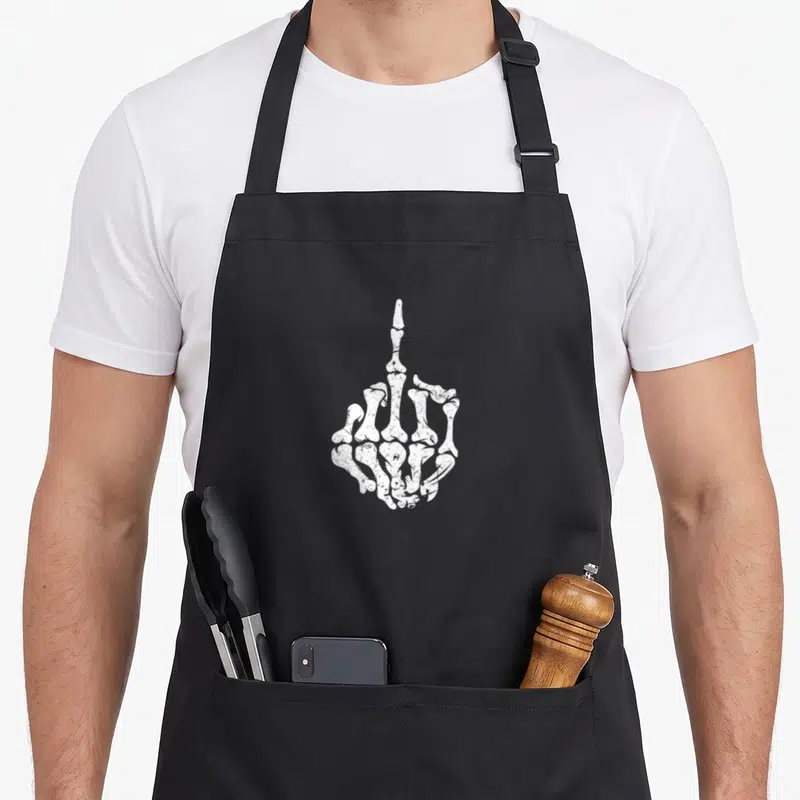 Tablier de cuisine noir avec illustration blanche d'une main squelettique faisant un doigt d'honneur.