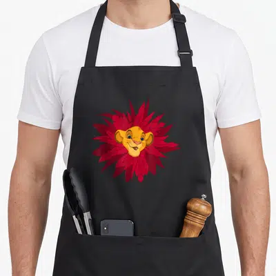 Tablier de cuisine noir avec le visage de Simba entouré de feuilles rouges stylisées formant une mane florale.