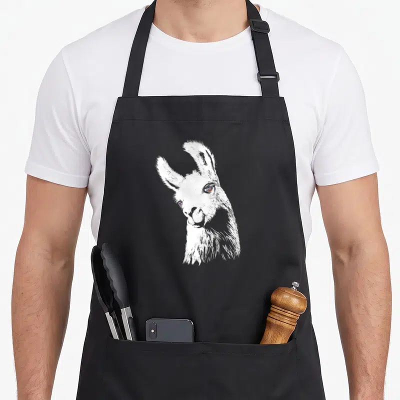 Tablier de cuisine noir avec un joli lama dessiné à la main aux yeux expressifs et au col en V stylisé.