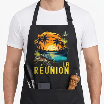 Tablier de cuisine noir avec carte de La Réunion, tortue nageante et texte jaune en bas.