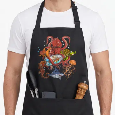 Tablier de cuisine noir avec illustration colorée d'un poulpe, d'un requin, d'une tortue, d'une méduse et d'un hippocampe.