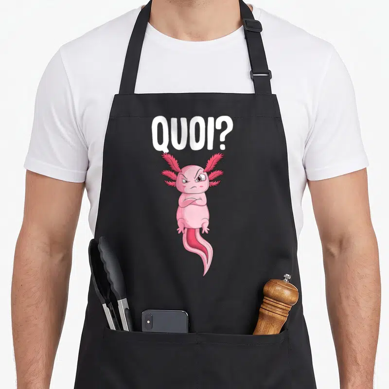 Tablier de cuisine noir avec un axolotl rose aux bras croisés et l'inscription QUOI en lettres blanches.