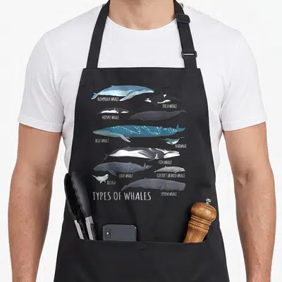 Tablier de cuisine noir avec illustration colorée de dix espèces de baleines et mammifères aquatiques disposées verticalement.
