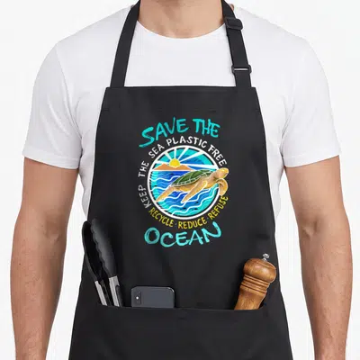 Tablier de cuisine noir avec une illustration circulaire d'une tortue de mer et des slogans militants en bleu et blanc.